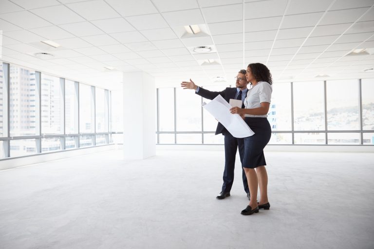 Businesspeople Meeting To Look At Plans In Empty Office