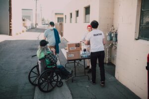 a group of people pushing a person in a wheelchair with boxes on it